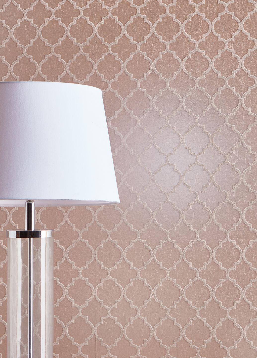 A rosewood-coloured glass bead wallpaper with a trellis pattern behind a table lamp with a white shade