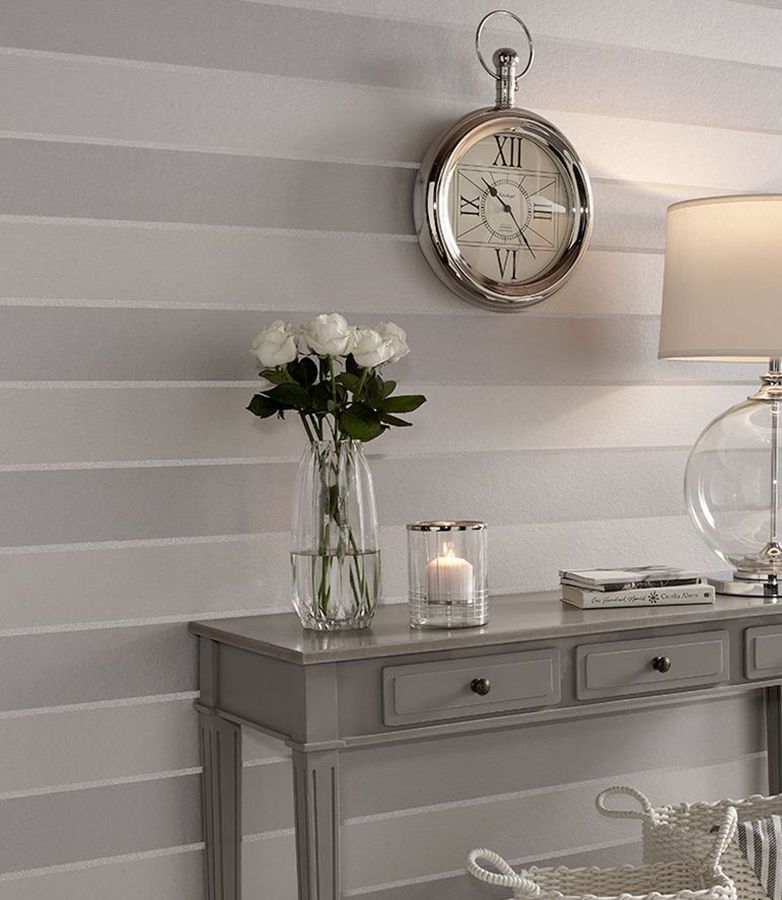 Papel de parede cinzento com listras horizontais de pérolas de vidro por trás de uma mesa de apoio