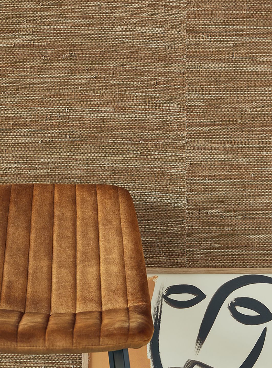A brown grass wallpaper on the wall behind a brown armchair