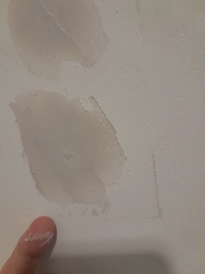 Main détectant des bosses sur un mur avant d'appliquer de l'enduit
