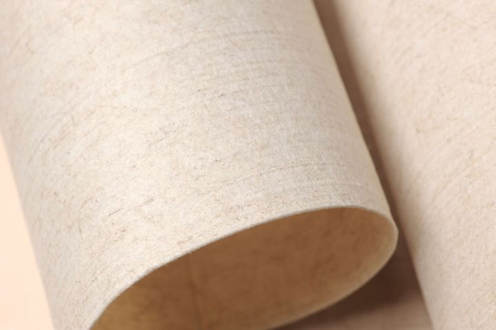 Close-up of a roll of Veruso Lino, a compostable wallpaper with a natural linen texture
