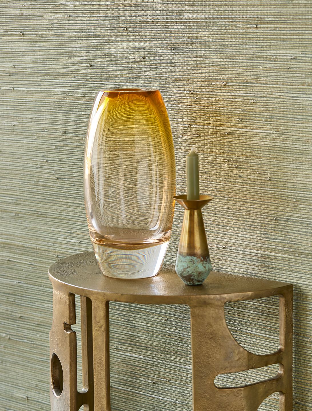 A reed-green grass wallpaper on the wall behind a small table with a vase